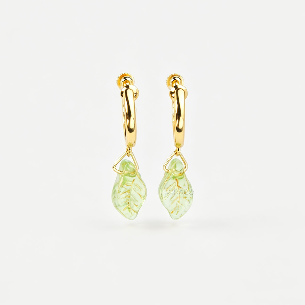 gold clip-on hoop earrings with light green carved glass leaf drops featuring an adjustable screw back for non-pierced ears.