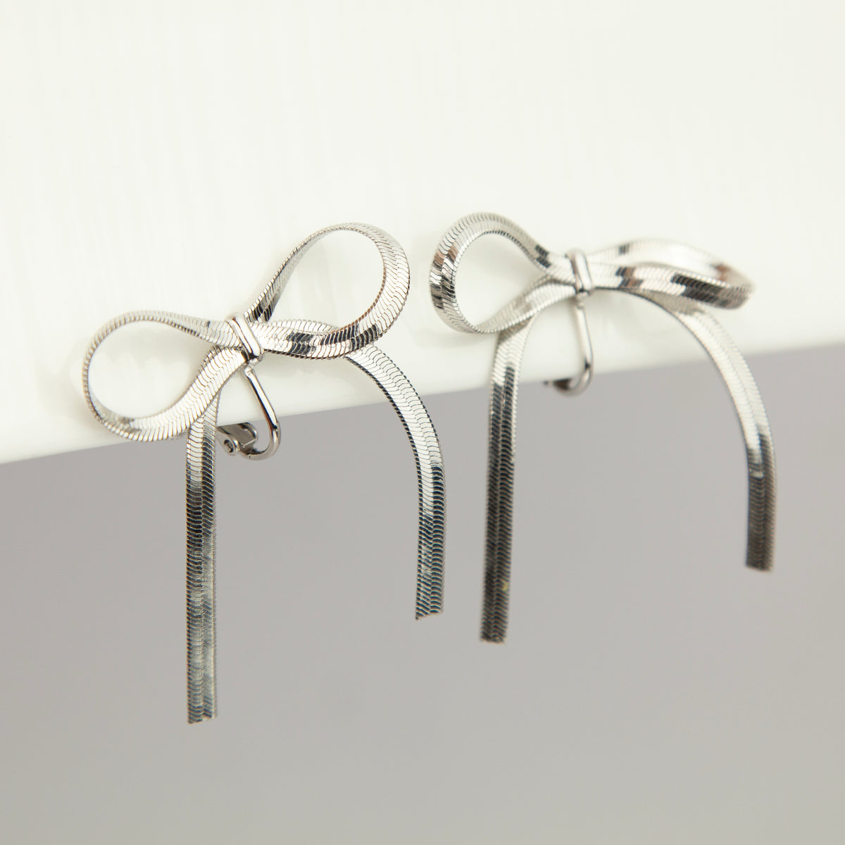 fluid silver snake chain ribbon bow clip-on earrings with adjustable screw backs for non-pierced ears.