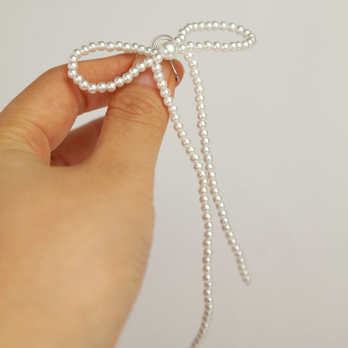 long cascading pearl bow clip-on dangle earrings with silver spring coil backs for non-pierced ears.