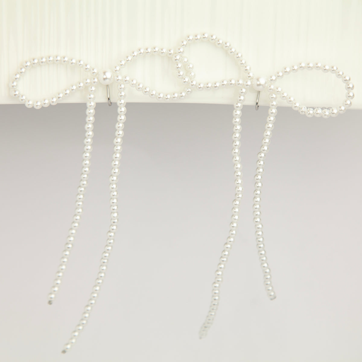 long cascading pearl bow clip-on dangle earrings with silver spring coil backs for non-pierced ears.