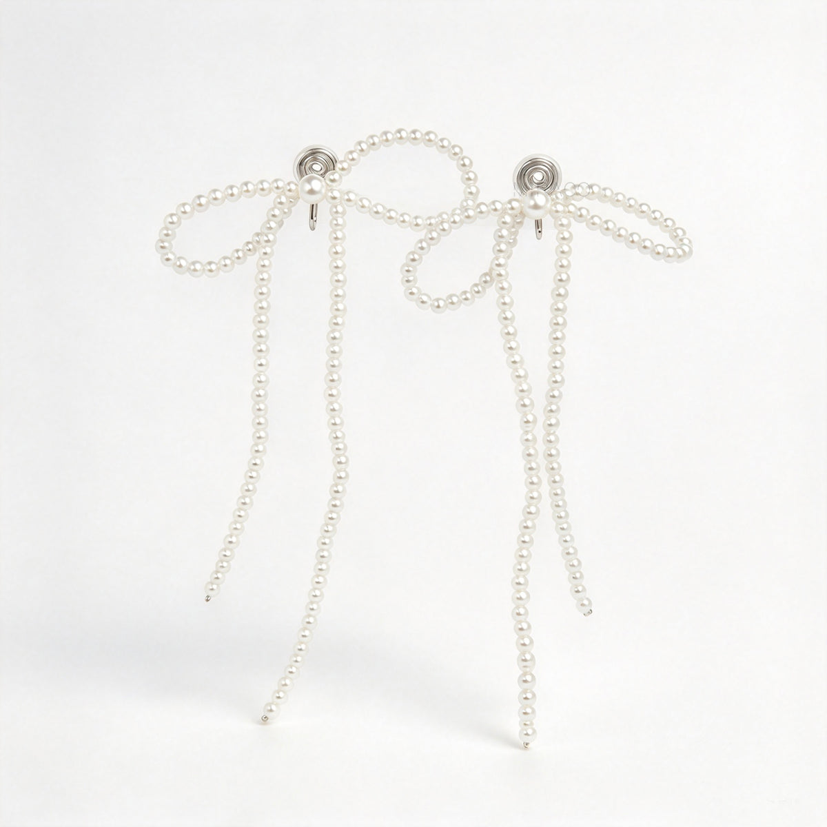 long cascading pearl bow clip-on dangle earrings with silver spring coil backs for non-pierced ears.