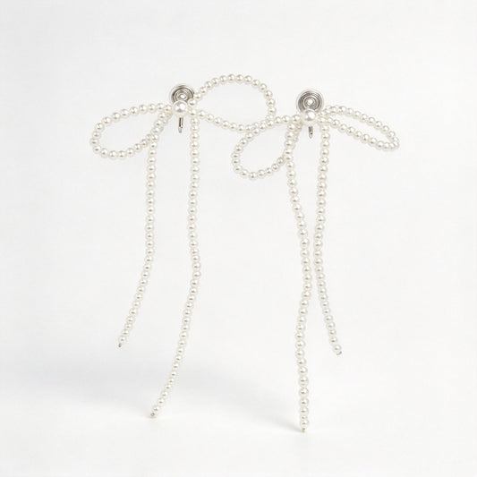 long cascading pearl bow clip-on dangle earrings with silver spring coil backs for non-pierced ears.