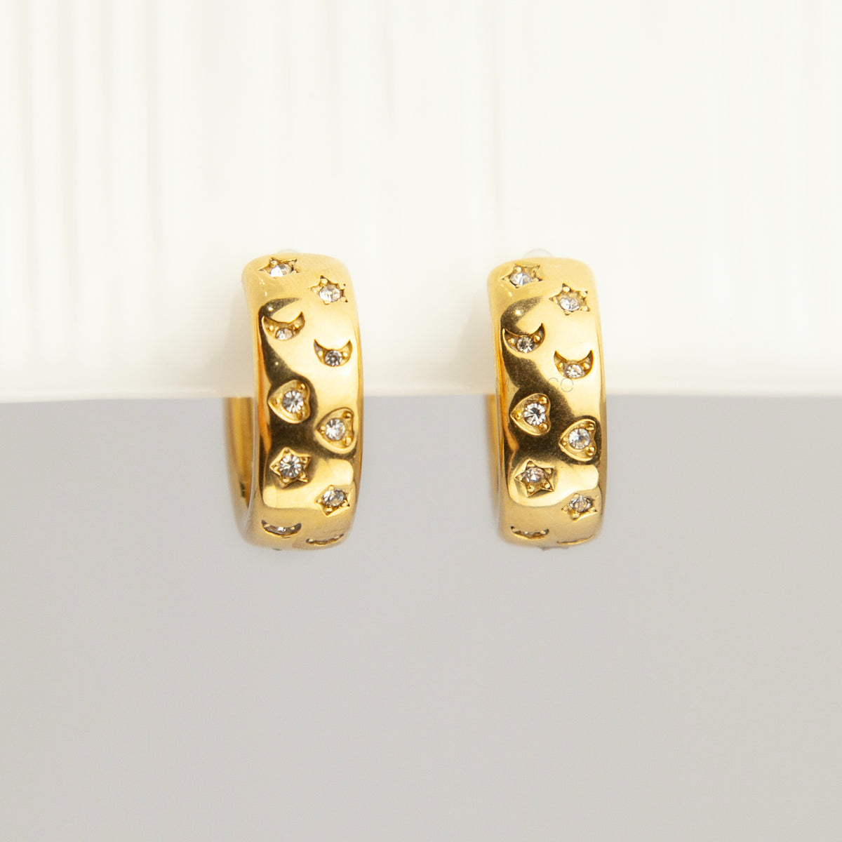 gold celestial star and moon cubic zirconia chunky hoop clip-on earrings with invisible clear resin backs for non-pierced ears.