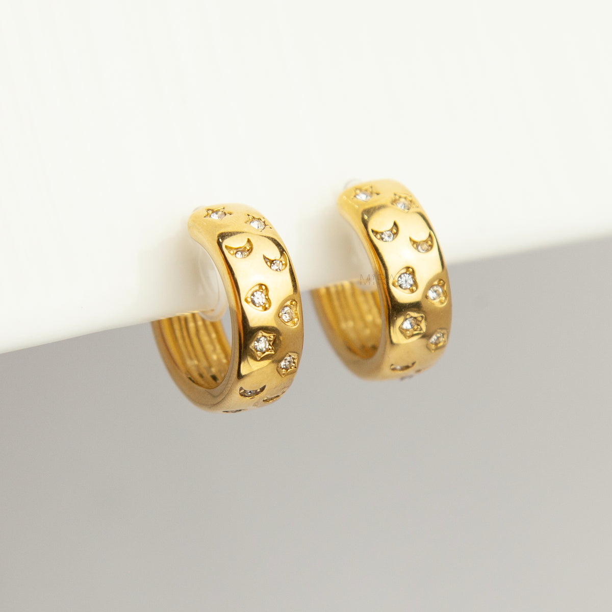 gold celestial star and moon cubic zirconia chunky hoop clip-on earrings with invisible clear resin backs for non-pierced ears.