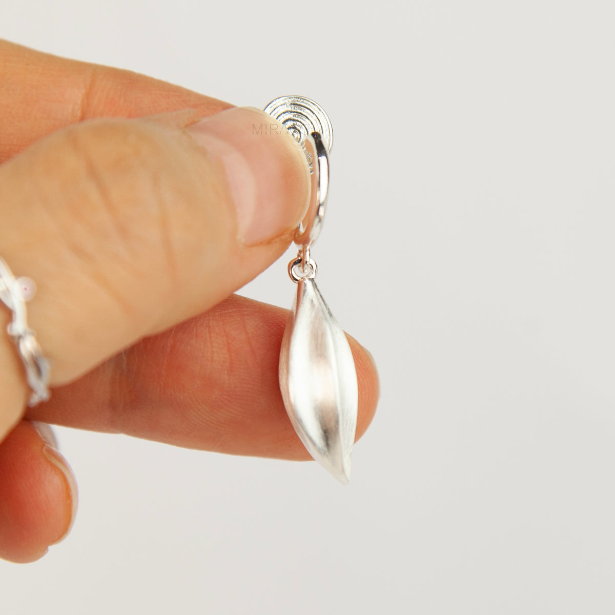 silver clip-on hoop earrings with brushed leaf drop pendants featuring a spring coil back for non-pierced ears.