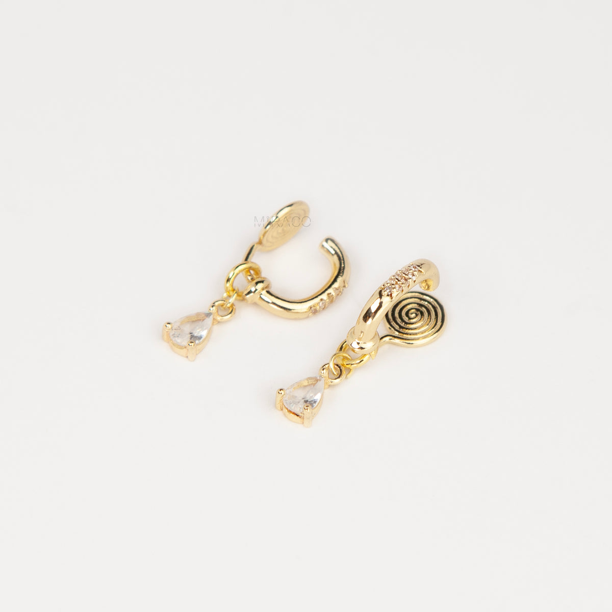 Gold and silver huggie clip-on hoop earrings with pavé cubic zirconia and teardrop CZ drop pendants featuring coil backs for non-pierced ears.