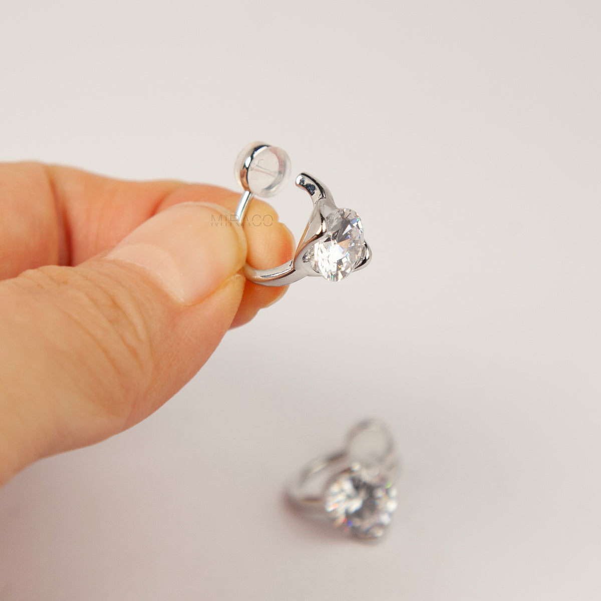 Silver solitaire cubic zirconia clip-on earrings with soft round silicon backings for non-pierced ears.