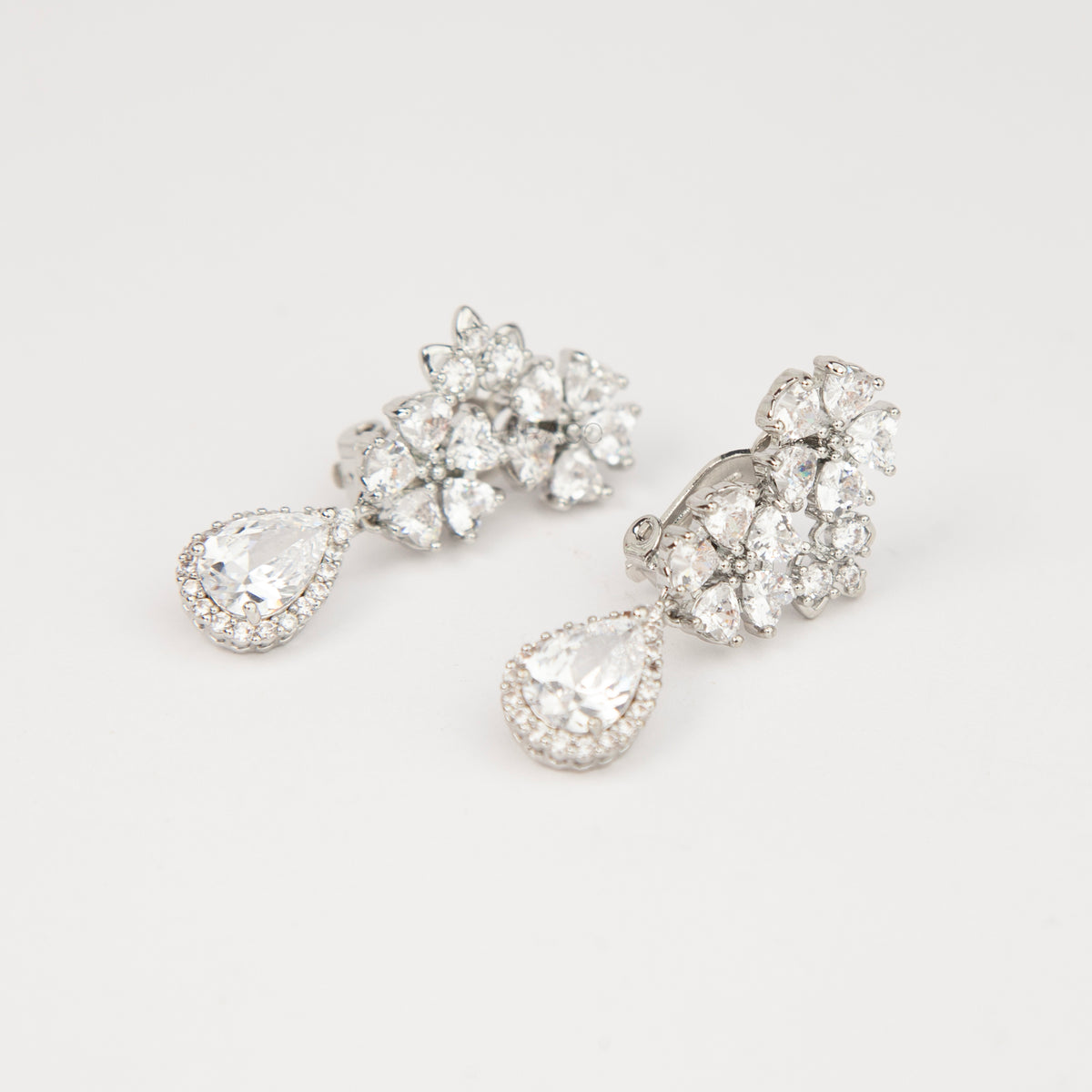 Silver floral cluster clip-on earrings featuring a halo pear-cut cubic zirconia teardrop with paddle backs.