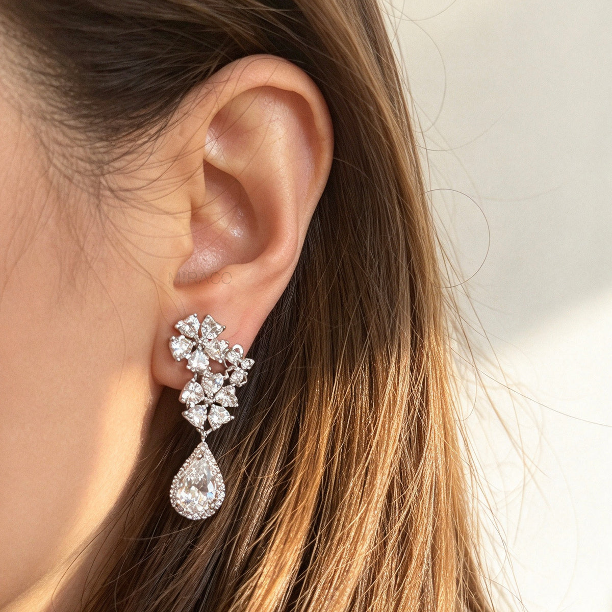 Silver floral cluster clip-on earrings featuring a halo pear-cut cubic zirconia teardrop with paddle backs.