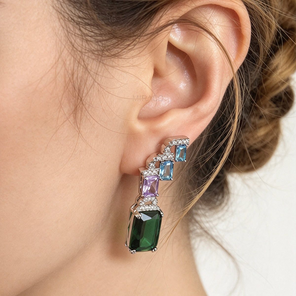 Art deco style multicolor clip-on drop earrings with blue, purple, and green emerald-cut crystals and invisible clear backs.