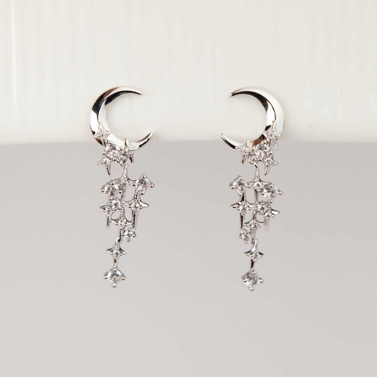 silver celestial crescent moon and starburst dangle clip-on earrings set with cubic zirconia and coil back non-pierced closure