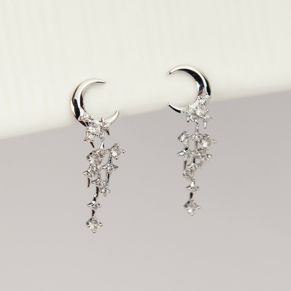 silver celestial crescent moon and starburst dangle clip-on earrings set with cubic zirconia and coil back non-pierced closure