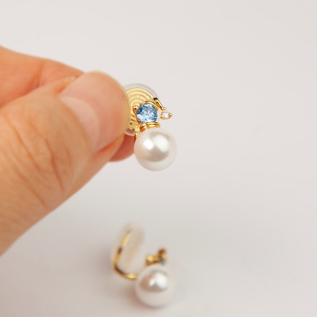 winter snowman pearl drop clip-on earrings featuring a gold hat topper set with a sparkling blue crystal and coil back non-pierced closure