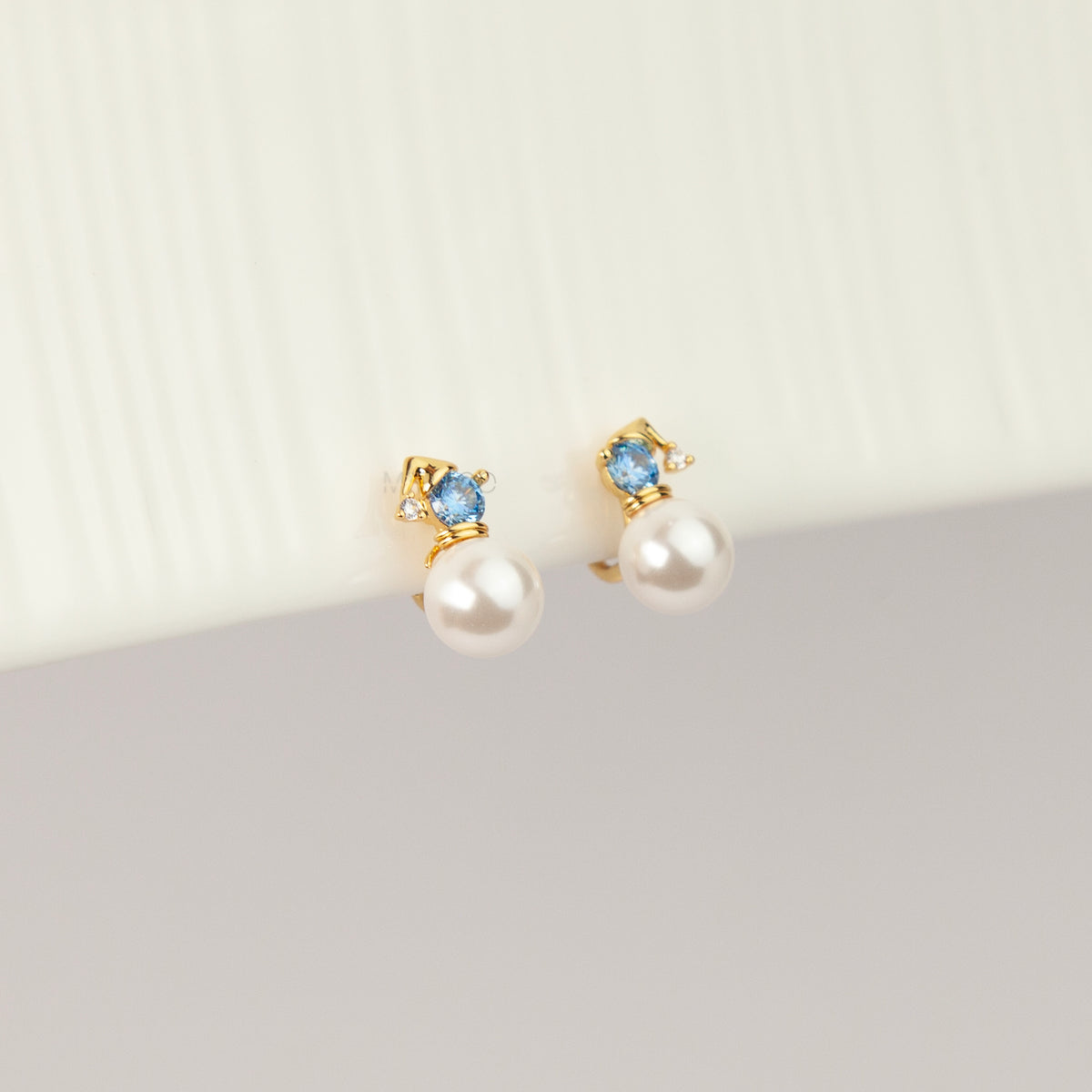 winter snowman pearl drop clip-on earrings featuring a gold hat topper set with a sparkling blue crystal and coil back non-pierced closure