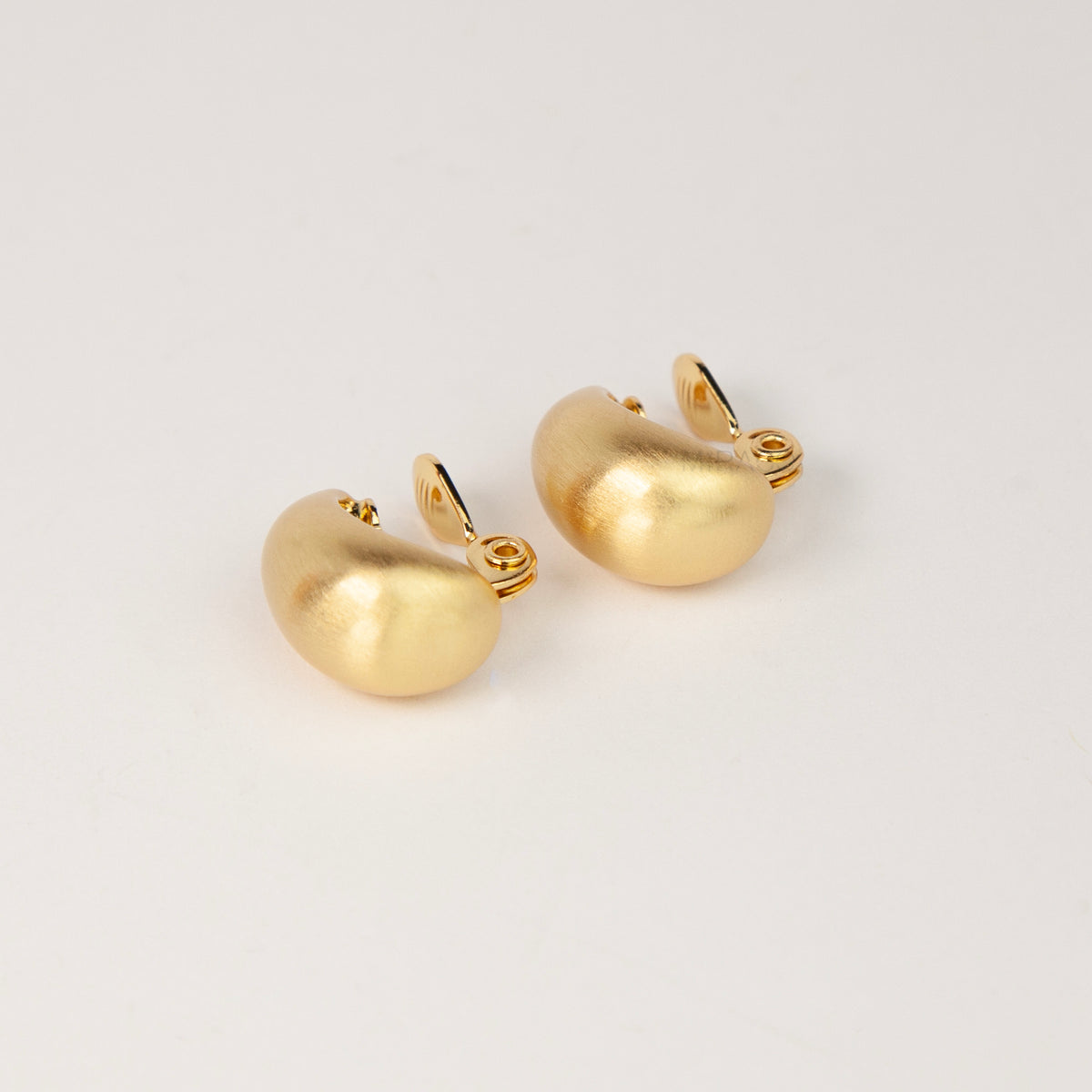 brushed matte gold curved dome huggie clip-on earrings with paddle clip back closure for unpierced ears.