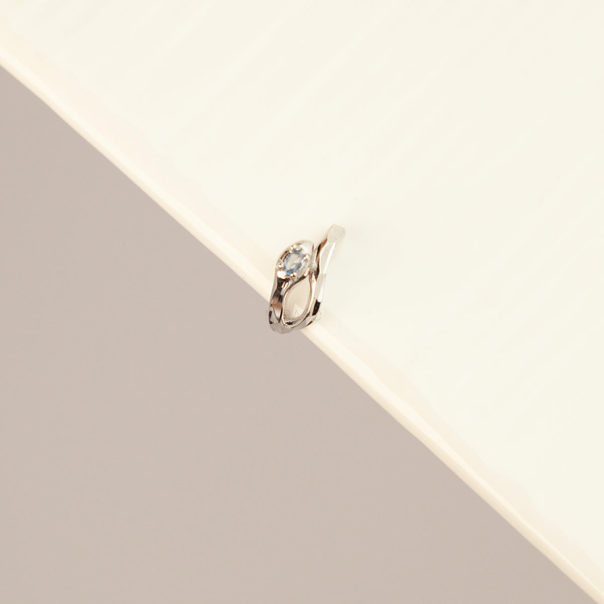 S925 sterling silver organic wave ear cuff clip-on featuring a small pale blue crystal stone worn on the conch of an unpierced ear.