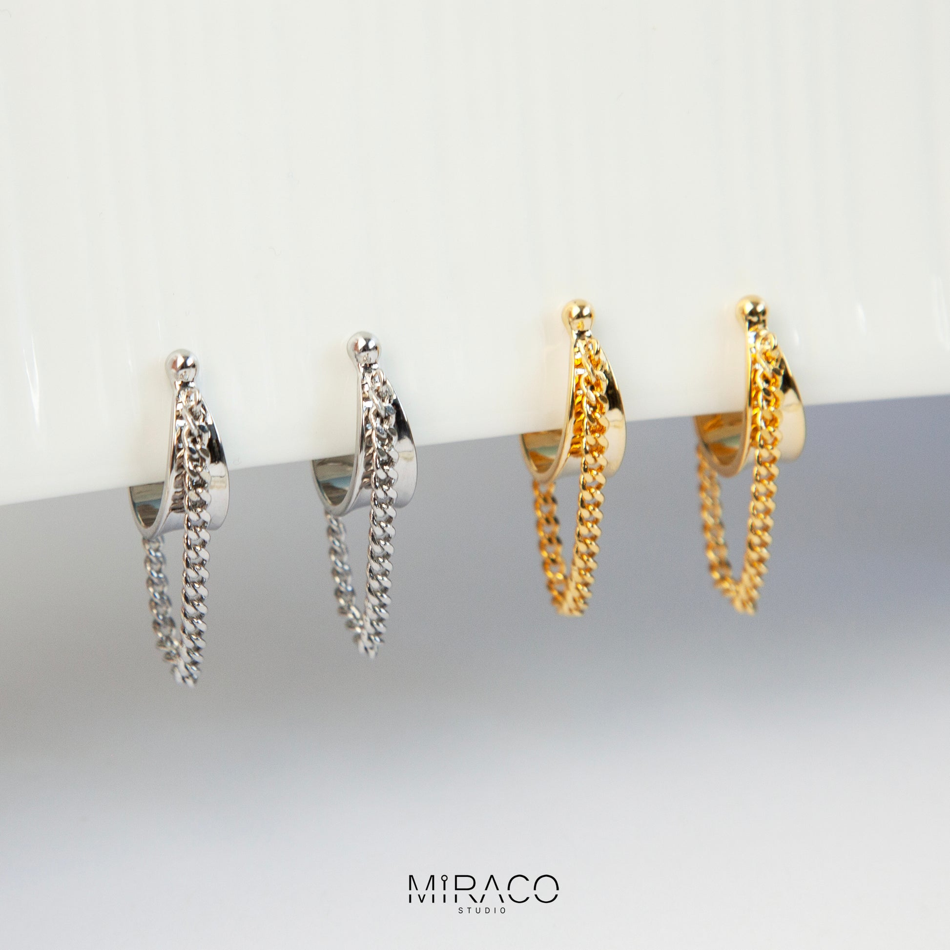 Hoop Clip-On Earrings with a Draped Chain, two in gold-tone and two in silver-tone, showing the Spring Coil Back.