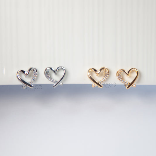 Delicate Sparkle, No Piercing Needed.

These elegant heart-shaped clip-on earrings feature a dainty open-heart design, set with tiny pavé diamond-style stones that catch the light beautifully. Whether you choose gold or silver, these small stud earrings bring just the right amount of sparkle to your everyday look.

Finished with comfortable coil-back clips, they’re designed for a snug fit and easy wear — perfect for anyone without pierced ears.