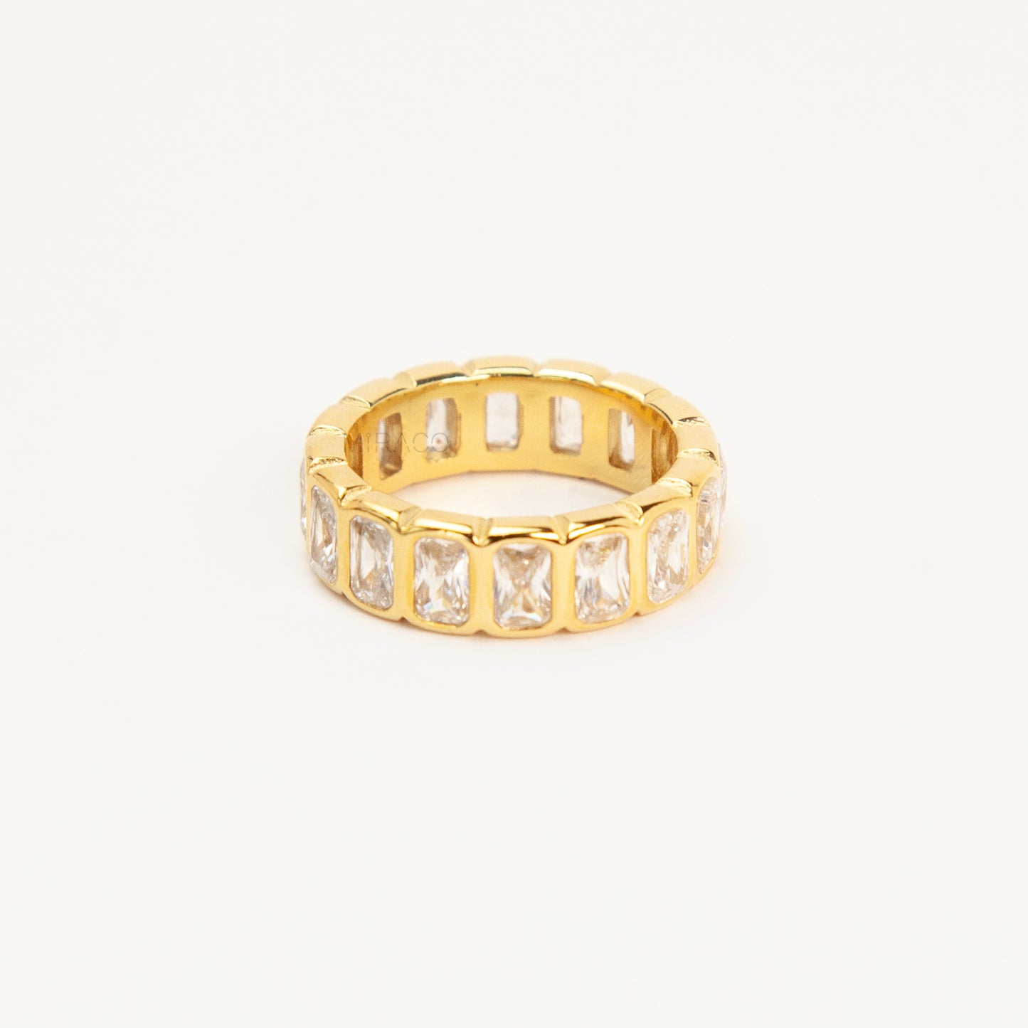 A polished gold-tone stainless steel eternity band ring featuring a continuous row of bezel-set emerald-cut clear crystals